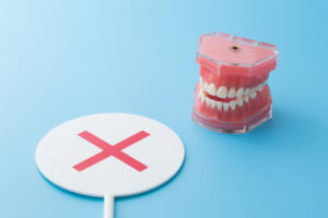 歯の模型とバツマークの札,歯科のデメリットのイメージ画像