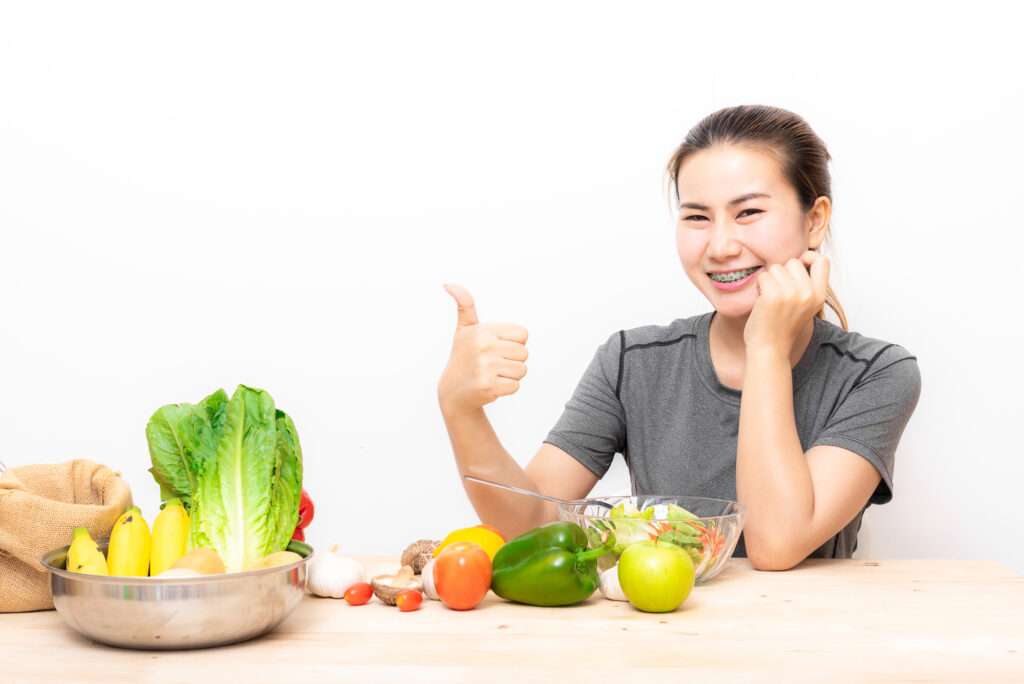 歯列矯正している女性と野菜の写真